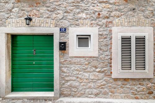 a stone building with a green door and two windows at Falcons Nest in Šibenik