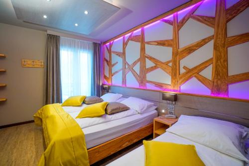 two beds in a room with purple lighting at Aktivhotel Santalucia in Nago-Torbole
