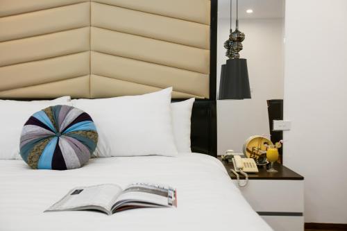 a book laying on a bed with a headboard at Splendid Star Grand Hotel and Spa in Hanoi