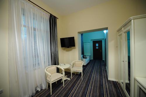 a room with two chairs and a table and a tv at Hotel Royal Craiova in Craiova