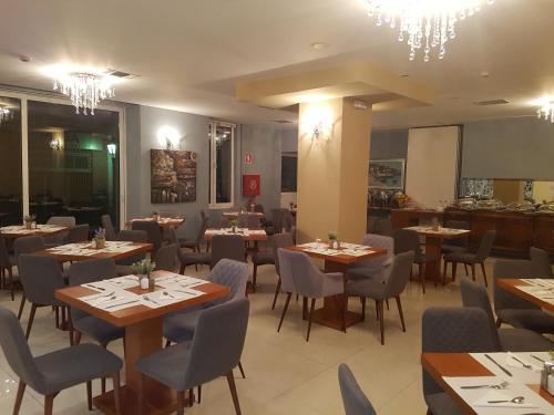 a dining room with tables and chairs and chandeliers at Grand Olympic Hotel Loutraki in Loutraki