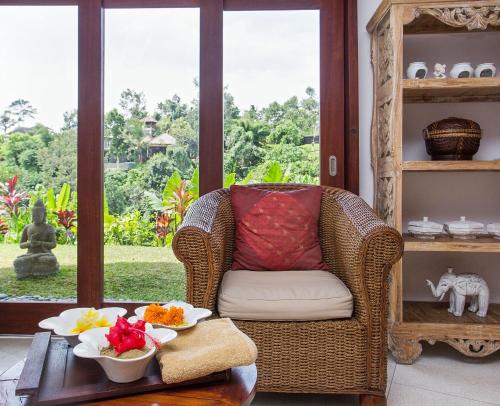 a room with a chair and a table with food on it at Amori Villas in Ubud