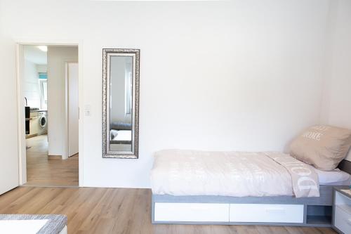 a white bedroom with a bed and a mirror at Holidayapartment Rüsselsheim in Rüsselsheim