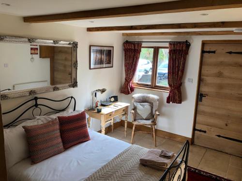 Schlafzimmer mit einem Bett, einem Schreibtisch und einem Spiegel in der Unterkunft Finchden Barn in Tenterden