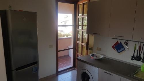 a kitchen with a refrigerator and a door to a yard at La Vigna For Family in La Maddalena