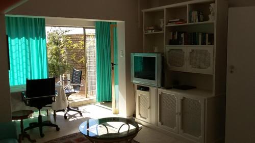 sala de estar con TV, mesa y ventana en Brooklyn Lodge, en Pretoria