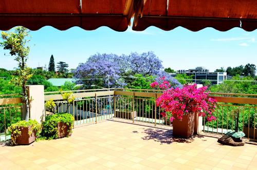 einen Balkon mit rosa Blumen und einem Zaun in der Unterkunft Brooklyn Lodge in Pretoria