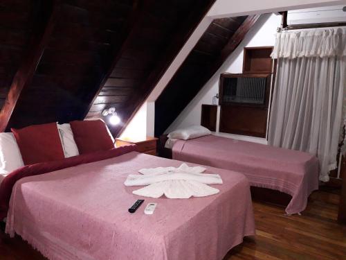 2 camas en una habitación con sábanas rosas y toallas en Petit Hotel Caraguata en Puerto Iguazú