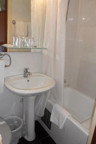 a white bathroom with a sink and a shower at Hotel Paulista in Porto