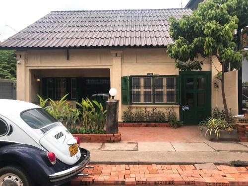 a house with a car parked in front of it at Barn1920s Hostel in Vientiane