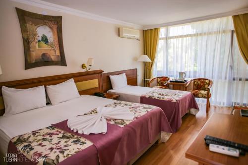 Habitación de hotel con 2 camas y mesa en Troia Tusan Hotel en Çanakkale