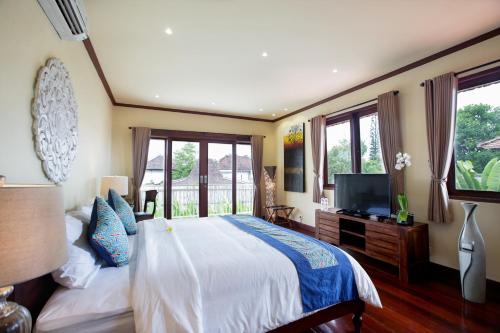 a bedroom with a large bed and a television at Villa Chambertin in Seminyak