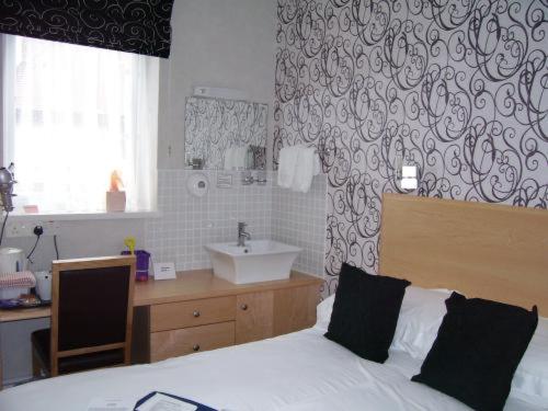 a bedroom with a bed and a bathroom with a sink at The Royal Bridlington in Bridlington