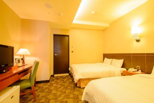 a hotel room with two beds and a desk and a television at LA HOTEL- Liuhe Fusing in Kaohsiung