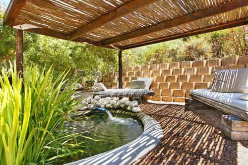 a patio with a pond and a wooden pergola at Dreamhouse Guest House in Hout Bay