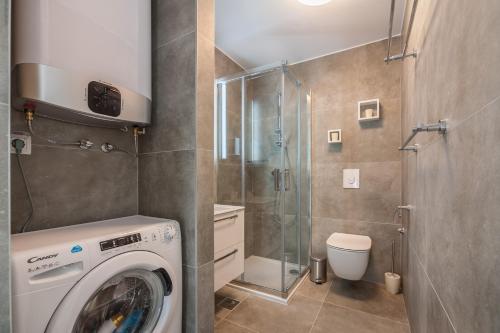 a bathroom with a washing machine and a shower at City Vibe Studios in Zadar