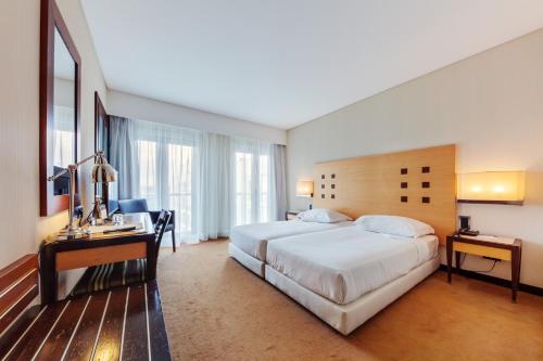una camera d'albergo con un grande letto e una scrivania di Hotel Lux Fatima a Fátima