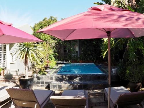 a swimming pool with a red umbrella and chairs and a swimming pool at Hillview Boutique Apartments in Knysna