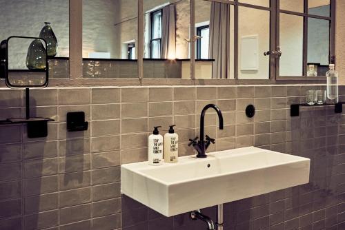 a bathroom with a white sink and a mirror at Fisher's Loft Hotel in Lübeck