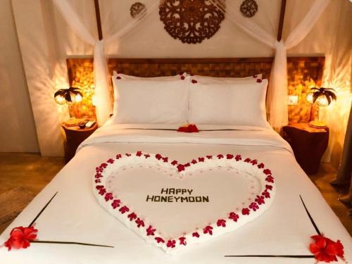 a heart shaped bed with a happyhuvention sign on it at Sandy Heaven Maldives in Gulhi