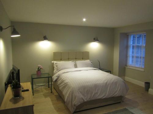 a bedroom with a bed with two tables and two lights at The Apartment, Lower Ground Floor, Clarendon Place in Leamington Spa