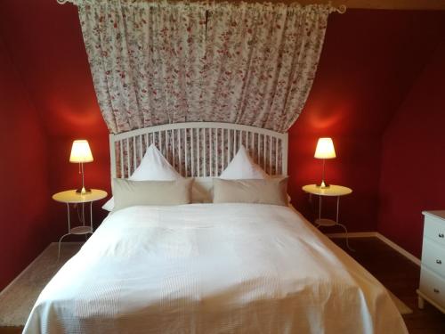 a bedroom with a white bed with red walls and two lamps at Parkland-Haus Dalwitz in Walkendorf