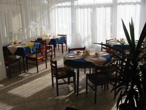 a dining room with tables and chairs and windows at Villa Mediterran in Hévíz