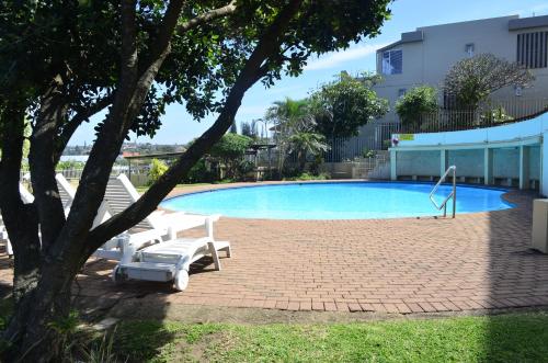 una piscina con una sedia e un albero di Sea View Holiday Flat - 16 La Luce Margate a Margate