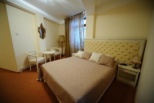 a bedroom with a bed and a table and a window at Hotel Royal Craiova in Craiova