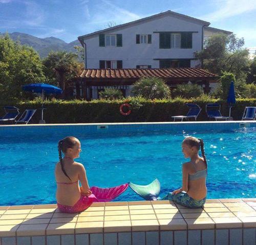 two young girls sitting next to a swimming pool at B&B Da Pio in Pietrasanta