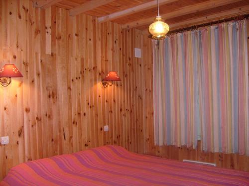 una camera da letto con pareti in legno e un letto con lenzuola viola di Gîte meublé Les Centaurées a Saint-Martin-en-Vercors