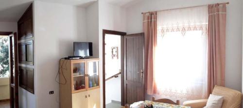 ein Wohnzimmer mit einer Tür, einem TV und einem Fenster in der Unterkunft Appartamento Ottiolu Mare in Porto Ottiolu