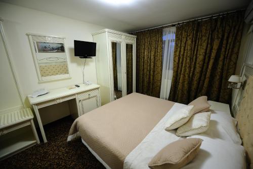 a bedroom with a bed and a desk and a television at Hotel Royal Craiova in Craiova