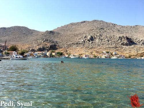 a body of water with houses and boats in it at Korali in Symi