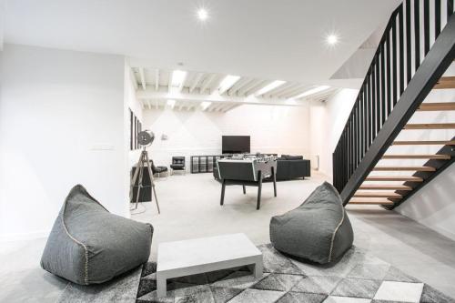een woonkamer met een trap, stoelen en een tafel bij NOCNOC - La Villa Cachee in Lille