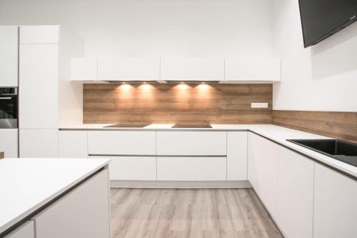 a white kitchen with white cabinets and wooden floors at NOCNOC - La Villa Cachee in Lille