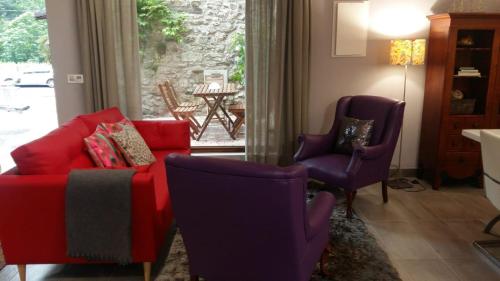 a living room with a red couch and two purple chairs at Casas La Xiuca in Corras de la Puente