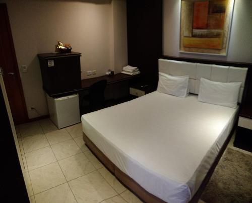 a bedroom with a white bed and a desk at Hotel Luni in Sao Paulo