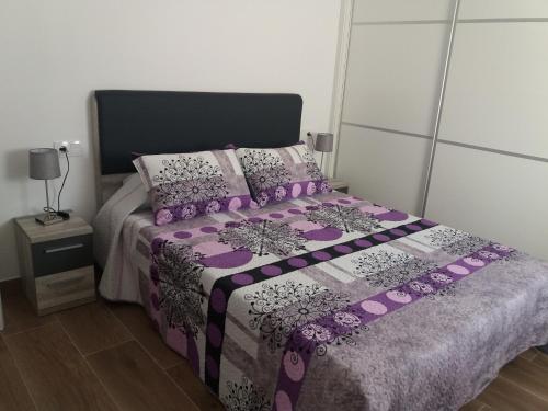 1 dormitorio con 1 cama con edredón y almohadas de color púrpura en Vinaròs junto al mar, en Vinarós