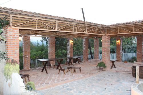 a pavilion with tables and benches on a brick patio at Guest House Daviti in Zestafoni