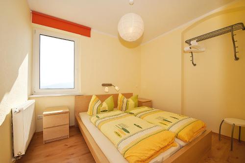 a bedroom with a bed with yellow sheets and a window at Panorama-Apartments Weinberghaus in Mittelndorf