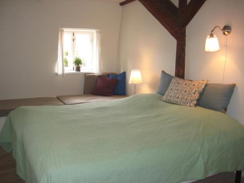 een slaapkamer met een groot groen bed en een raam bij Købmandsgårdens B&B Kerteminde in Kerteminde
