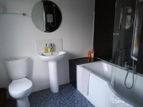 a bathroom with a sink and a toilet and a bath tub at Riverside Cottage in Carrickfergus