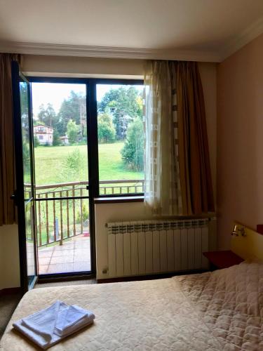 a bedroom with a bed and a large window at Daf Trans Hotel in Peshtera