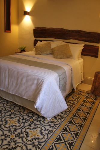 a bedroom with a large bed with white sheets and a rug at Verde Morada in Valladolid