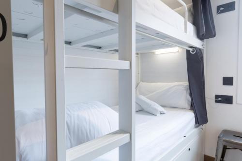 1 dormitorio con literas blancas en una habitación en Airhostel Barcelona Airport 24h, en El Prat de Llobregat