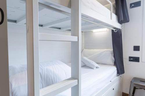 a bedroom with white bunk beds in a room at Airhostel Barcelona Airport 24h in El Prat de Llobregat