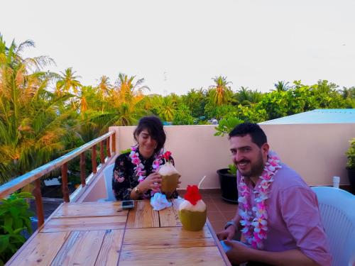 a man and a woman sitting at a table with drinks at Nemo Inn in Omadhoo