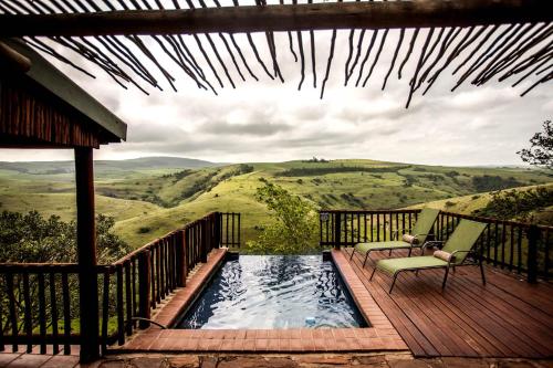 a deck with a pool and two chairs on a porch at Gwahumbe Game & Spa in Mid Illovo