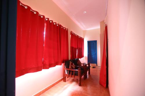 a hallway with red curtains and a chair in a room at Zingle Stay Airport Hotel in Chennai